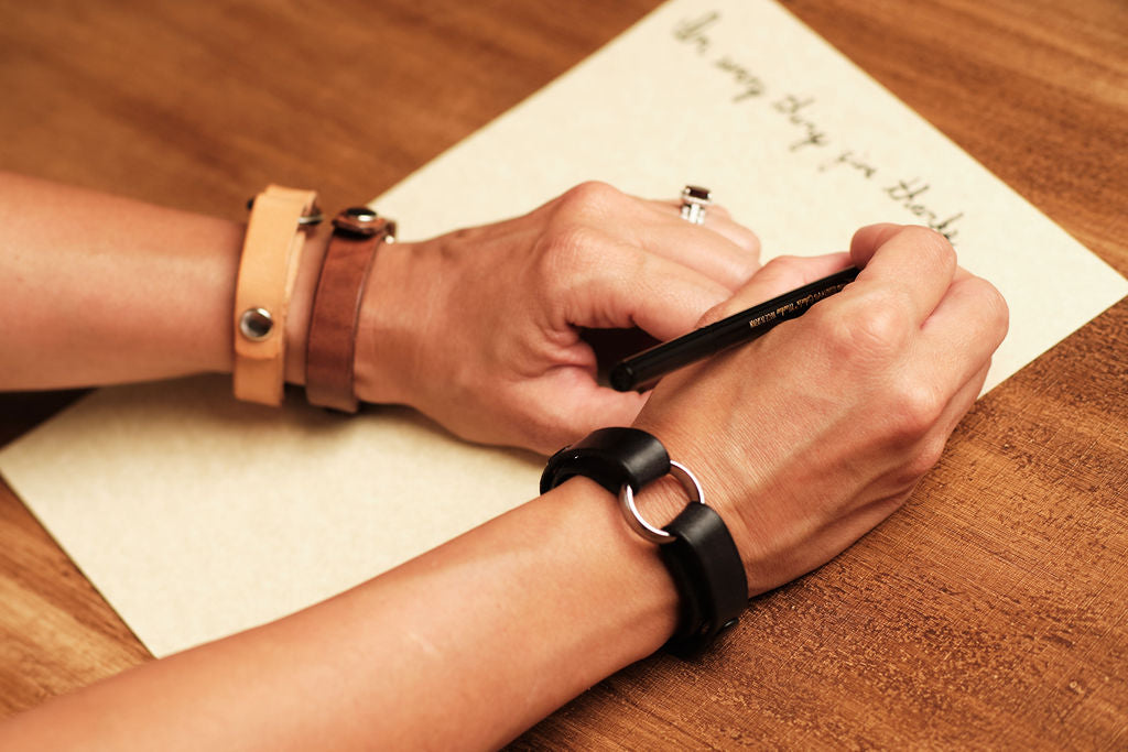 Memorial leather bracelets for widows and remembrance—handcrafted black, brown, and tan keepsake bracelets worn while writing a heartfelt letter, meaningful grief jewelry and ring holder accessories.